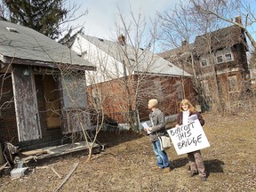 Sandwich residents in Windsor, Ont. held a neighbourhood walking tour and press conference Wednesday, April 2, 2014, to bring attention to the Canadian government's recent approval of the environmental assessment for a twin span of the Ambassador Bridge. Caroline Taylor and Taajai Travis are in the backyards of a boarded up home on Indian Rd. (DAN JANISSE/The Windsor Star)