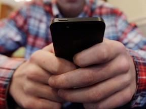 A teen uses his smartphone to text a message. (Associated Press files)
