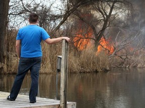 Chris Laforet, a resident of Rivervilla Crt., in LaSalle, watches as a wild fire approaches his property off Turkey Creek, Saturday, April 12, 2014.  (DAX MELMER/The Windsor Star)