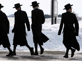 Members of the Lev Tahor ultra-orthodox Jewish sect walk down a street while an emergency motion in the child custody case is held at the courthouse in Chatham, Ont., Wednesday, March 5, 2014. THE CANADIAN PRESS/Dave Chidley