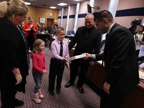 Mayor Eddie Francis presents Karrie Koekstat, left, Paisley Koekstat, Burke Koekstat and Peter Burke with an iPod after the family won a draw for participants in Snow Angels program during  city council meeting Windsor on Monday, April 7, 2014.                          (TYLER BROWNBRIDGE/The Windsor Star)