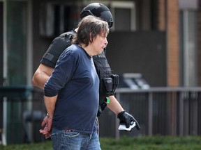 A Windsor police ESU officer escorts a stabbing suspect out of the Pruefer Court South apartment building after he refused to surrender to police, Sunday, April 13, 2014.  (DAX MELMER/The Windsor Star)