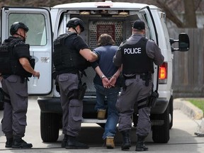 A stabbing suspect  is placed into a prisoner escort vehicle by Windsor police ESU officers after a standoff with police, Sunday, April 13, 2014.  (DAX MELMER/The Windsor Star)