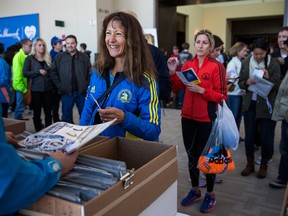 A woman receives her Boston Marathon race bib and race information on April 20 in Boston. Those runners who don't acquire their bibs via legitimate means are known as bandits. (Andrew Burton / Getty Images)
