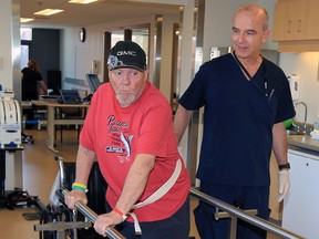 Patient Robert Graham is assisted by physiotherapist Carlo Giovanatti at Hotel-Dieu Grace Healthcare on Tuesday. MPP Teresa Piruzza attended the Prince Road facility to announce $8.25 million in funding for a new hospital unit to help get patients home quicker.  (NICK BRANCACCIO / The Windsor Star)