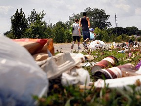 A young family walks past a long stretch of garbage that remains along the Ford Test Track in Windsor, Ont.,on Aug 4, 2009.   City of Windsor workers are on their second week back at work following the bitter CUPE Strike.  (JASON KRYK/ THE WINDSOR STAR)