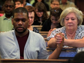 Austin Osula, left, and Spomenka Miskovic hold hands during a vigil service at All Saints' Anglican Church to pray for the safe return of hundreds of kidnapped Nigerian school girls Monday May 12, 2014. (NICK BRANCACCIO/The Windsor Star)