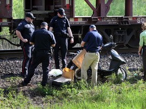 Windsor Police and CP Rail Police place evidence in paper bags where a body was found on railway tracks between McDougall Avenue and Ouellette Avenue overpass Wednesday May 21, 2014.   (NICK BRANCACCIO/The Windsor Star)