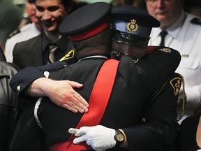 Windsor police Const. Mike Akpata (L) hugs O.P.P. Const. Michael Atkinson (brother of John Atkinson) during remembrance ceremony on Monday, May 5, 2014, at the Windsor Police headquarters in Windsor, Ont.   (DAN JANISSE/The Windsor Star)