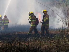 Firefighters walk through smoke-filled fields after battling a brush fire in LaSalle on May 22, 2014. (Nick Brancaccio / The Windsor Star)