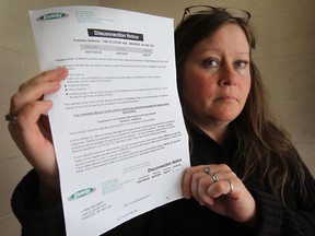 Lynne Meanney displays a disconnection notice she recently received from Enwin Utilities. The company recently re-assessed her meter reading and found she had been under-billed for water over the last 20 years. She's fighting about $360 in retroactive charges.  (DAN JANISSE/The Windsor Star)