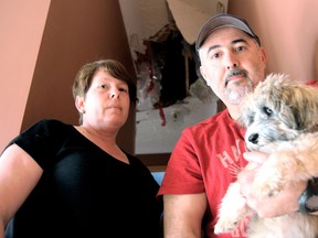 LaSalle residents Tony and Chantelle Mancinone hold their pet dog Titan on the stairs leading up to where the lightning came through the ceiling on Tuesday, May 27, 2014. (JOEL BOYCE/The Windsor Star)