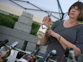 Katy O'Brien, from Cooper's Hawk Winery, sells bottles of wine on the opening day of the Downtown Farmer's Market at Charles Clark Square in downtown Windsor, Saturday, May 31, 2014.  T(DAX MELMER/The Windsor Star)