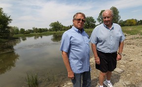Bill Fellows, left, and Larry Brushett stand near the pond behind their condo building in Tecumseh on Monday, May 26, 2014. Fellow and Brushett would like to save the pond but a development is slated to fill it in.             (TYLER BROWNBRIDGE/The Windsor Star)