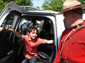 RCMP Const. Jeff Town, right, interacts with Ahmed Tabib, 8, while showing him inside an RCMP vehicle at the Junior Law Enforcement Academy at the Windsor Mosque, Saturday, May 31, 2014.  The event was hosted by the RCMP and the Windsor Islamic Association.  (DAX MELMER/The Windsor Star)