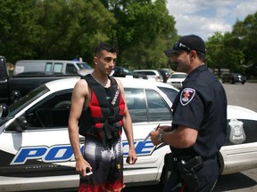 A Windsor police officer talks with Mustafa Alkaissy, 21, who aided in the rescue of two boys whose Sea-Doo capsized in the Detroit River, Saturday, May 24, 2014.  (DAX MELMER/The Windsor Star)