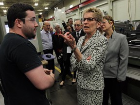 Premier Kathleen Wynne talks with machinist John Gay during a tour of Omega Tool Corp. in Windsor on May 21, 2014. Windsor West MPP Teresa Piruzza (far right) looks on. (Tyler Brownbridge / The Windsor Star)