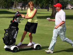 Golfer Nesta Lacey, left, goes for a spin on GolfBoard, the electric scooter that Roseland golf pro Randy McQueen controls with a control gun. (NICK BRANCACCIO/The Windsor Star)