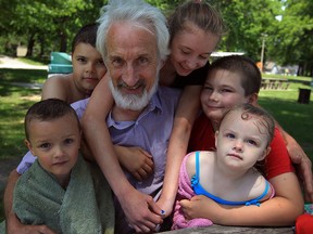 Grandpa Dennis Dicks receives some generous hugs from grandchildren Seth Entwistle, 7, left, Evan Entwistle, 10, Cierra Entwistle, 15, Ethan Entwistle, 11, and Julia Entwistle,2, right, during a Father's Day picnic and swim at Mic Mac Park on Prince Road Sunday June 15, 2014. (NICK BRANCACCIO/The Windsor Star)