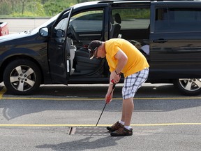 Dave Heino uses a fishing rod trying to recover a set of keys to his Chrysler minivan in the parking lot of WFCU Centre Tuesday June 17, 2014. Heino's keys slipped from the front seat of his van last Thursday and he met with City of Windsor mainenance workers Earl Hooey and George Thomas Tuesday morning to recover the keys. (NICK BRANCACCIO/The Windsor Star)