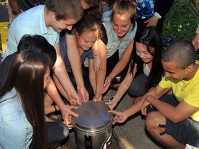 Riverside Secondary School time capsule is sealed and dropped into a concrete vault by students Alexis Provost, left, Steven Liu, Lucas Dodson, Ivana Jamina, Maggie Lyons, Tina Pham and Todd Pribanic, right. Behind, student Curtis Labutte, principal Mary Edwards and public board trustees Gale Simko-Hatfield and Cheryl Lovell and retired teacher Elliott Dunlop joined in the fun, Friday June 5, 2014. (NICK BRANCACCIO/The Windsor Star)