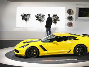 A visitor looks over engine options on display next to a 2015 Chevrolet ZO6 Corvette at the North American International Auto Show (NAIAS)  in Detroit, Michigan.