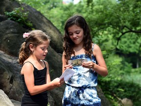 Piper and Tatum Sanders from Pittsburgh find money in an envelope as part of the Hidden Cash sacavenger hunt on June 14, 2014 in New York's Central Park. The frenzied hunt for large sums of cash hidden in public hit New York on Saturday, with $2,000 in envelopes stashed across Central Park and Brooklyn. The money comes from wealthy real estate investor Jason Buzi and a group of anonymous friends and began the hunts in San Francisco.(Timothy A. CLARY/AFP/Getty Images)