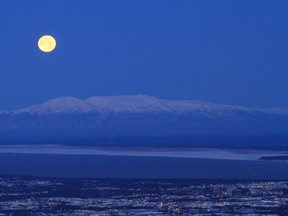 A full moon sets over Mount Susitna, also known as Sleeping Lady, in a view from the Glen Alps Trailhead on Sunday, Nov. 17, 2013, in Anchorage, Alaska.  (Associated Press files)