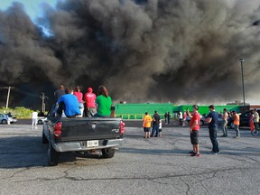 Onlookers gather in a parking lot to watch flames and smoke spill from the former Windsor Bumper Manufacturing Plant on June 25, 2014. (Jason Kryk / The Windsor Star)