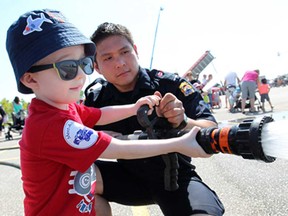 Evan Raymond, 3, gets help operating a fire hose from Windsor firefighter, Bruce Jean, during the 4th annual Meet A Machine in the WFCU Centre parking lot, Saturday, June 7, 2014.  (DAX MELMER/The Windsor Star)
