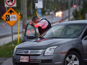 An RCMP officer rests his head at a roadblock in Moncton, N.B. on Thursday, June 5, 2014. Three RCMP officers were killed and two injured by a gunman wearing military camouflage and wielding two guns on Wednesday. Police have identified a suspect as 24-year-old Justin Bourque of Moncton. THE CANADIAN PRESS/Andrew Vaughan
