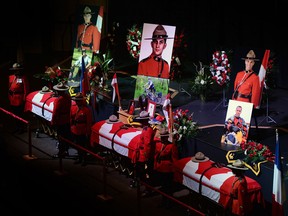 The caskets of Const. Dave Joseph Ross, 32, from Victoriaville, Que., left to right, Const. Douglas James Larche, 40, from Saint John, N.B. and Const. Fabrice Georges Gevaudan, 45, from Boulogne-Billancourt, France, sit in Wesleyan Celebration Centre during the public visitation in Moncton, N.B. on Monday, June 9, 2014. A regimental funeral will take place Tuesday for the three RCMP officers who were slain in Moncton last week. THE CANADIAN PRESS/Sean Kilpatrick