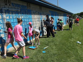 Volunteers with Our West End, a United Way supported initiative, along with Windsor Police, volunteer residents and students take part in a graffiti clean up at Mic Mac Park in Windsor on Saturday, June 14, 2014. The group painted a pair of walls to remove graffiti including painting the word community on to one of the walls.  (Tyler Brownbridge/The Windsor Star)