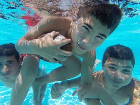 From left, Moe Youssef, 15, Hussein Fakih, 14, and Moe Komeiha, 14, play with the football while swimming at Lanspeary Pool, Sunday, June 22, 2014.   (DAX MELMER/The Windsor Star)