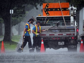 In the middle of a heavy downpour, City of Wndsor maintenance workers Conor Allard, left, and Nathan Sidoroff patch a small sinkhole on Tecumseh Road East at Gladstone Avenue TUESDAY July 8, 2014. (NICK BRANCACCIO/The Windsor Star)