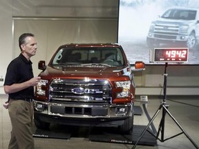 Ford Truck Group Marketing Manager Doug Scott stands next to the automaker's new aluminum-sided 2015 F-150 truck at the company's Development Center in Dearborn, Mich., Tuesday, July 22, 2014. The truck, which goes on sale this fall, is 732 pounds lighter than the outgoing model. Ford’s base truck with a 3.5-liter V6 engine, will get 283 horsepower, similar to a Chevrolet Silverado but lower than a Ram. But Ford says it will have more towing capacity than both rivals, at 7,600 pounds. (AP Photo)