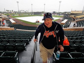 Ray Raymond, of Centerline, Mich., climbs to the seats under cover as rain falls at Joker Marchant Stadium before an exhibition spring training baseball game between the Detroit Tigers and the Philadelphia Phillies in Lakeland, Fla. (AP Photo/Gene J. Puskar)