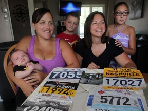 Moms Brandy Vaillancourt, left, and Phyllis MacIntyre have teamed up to launch a new business called Race Kids, a babysitting service for marathon runners, Tuesday July 22, 2014. Vaillancourt holds her newborn baby Pierce, 7 weeks, and son Ethan, 5, is behind.  MacIntyre's daughter, Emily, 9, at right.   (NICK BRANCACCIO/The Windsor Star)