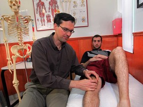 Physiotherepist John Spirou, left, checks the knee of Chris Kelly at the Spine Joint Bone and Muscle Walk-in Clinic at 1505 Ouellette Avenue Friday July 25, 2014. (NICK BRANCACCIO/The Windsor Star)