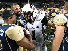 Ex-Lancer Matt Bucknor, left, greets Ottawa quarterback Henry Burris after their CFL game at Investors Group Field in Winnipeg, (Photo by Marianne Helm/Getty Images)