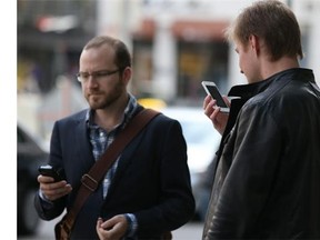 Two men use their smartphones. (Getty Images files)