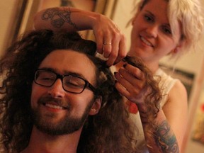 Nikki Antie of Pop Hair Gallery, right, ties up University of Windsor student Conor Allard's hair inside Villain's Beastro, Saturday, July 19, 2014. Allard, 23, raised over $1,100 for Welcome Centre for Women and plans to donate his hair to Wigs for Kids. (RICK DAWES/The Windsor Star)