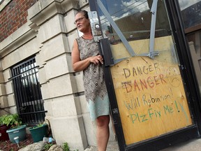Millie Hayward stands at the boarded up front door at the apartment building where she lives in in downtown Windsor on July 17, 2014.   (Tyler Brownbridge/The Windsor Star)