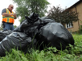 In this file photo, Dave Girard collects garbage bags left behind by collectors and talks to residence about the new hard container rules in Windsor on Wednesday, July 2, 2014.        (Tyler Brownbridge/The Windsor Star)