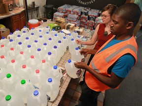 Demeeko Williams, Co-ordinator of the Detroit Water Brigade and volunteer Stephanie Howells sort through jugs of drinking water that will be distributed to those in need in Detroit, Michigan on July 9, 2014. (JASON KRYK/The Windsor Star)