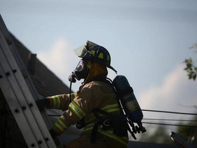 A Windsor firefighter climbs to the roof of a home at 2040 Ferndale Ave. on July 7, 2014. (Dax Melmer / The Windsor Star)