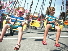 Lyla Reiss, 3, left, and Emma Gough, 4, take a turn on the swings at the Essex Fun Fest at the Essex Fair Grounds, Saturday, July 12, 2014.  (DAX MELMER/The Windsor Star)