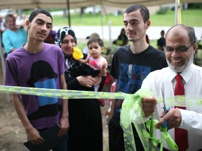 Mohamed Abujabal, right, along with his family, cuts the ribbon to his new home they received through Habitat for Humanity, Saturday, July 19, 2014.   (DAX MELMER/The Windsor Star)