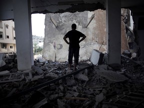 A Palestinian man looks at a destroyed house following an overnight Israeli missile strike in Gaza City Monday, July 14, 2014. Israel began airstrikes Tuesday against militants in the Hamas-controlled Gaza Strip in what it says was a response to heavy rocket fire out of the densely populated territory. The military says it has launched more than 1,300 airstrikes since then, while Palestinian militants have launched nearly 1,000 rockets at Israel. (AP Photo/Khalil Hamra)