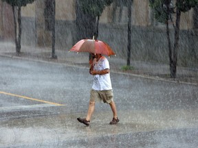 A pedestrian in downtown Windsor braves heavy rain in this July 2013 file photo. (Tyler Brownbridge / The Windsor Star)